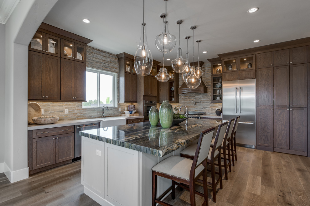 This is an example of a large traditional eat-in kitchen in Salt Lake City with an undermount sink, recessed-panel cabinets, dark wood cabinets, granite benchtops, grey splashback, ceramic splashback, stainless steel appliances, light hardwood floors, with island and brown floor.