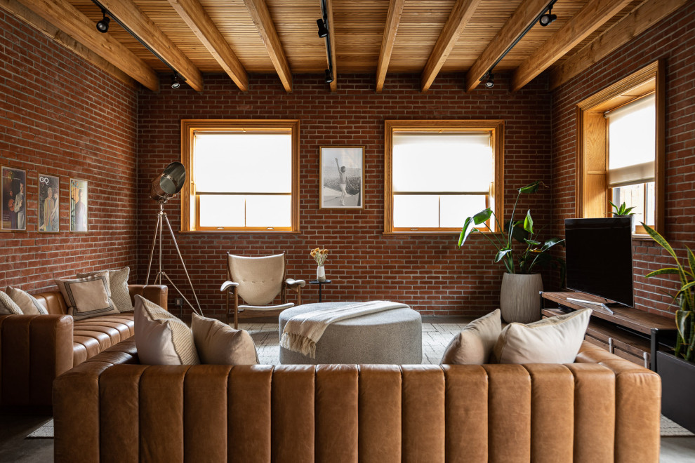 Inspiration for an industrial open concept living room in New York with red walls, concrete floors, a freestanding tv, grey floor, exposed beam, wood and brick walls.