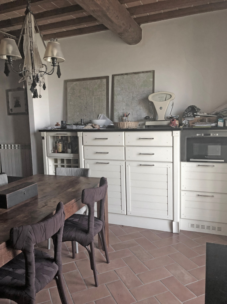 Inspiration pour une petite salle à manger ouverte sur le salon méditerranéenne avec un mur beige, tomettes au sol, aucune cheminée, un sol marron et poutres apparentes.