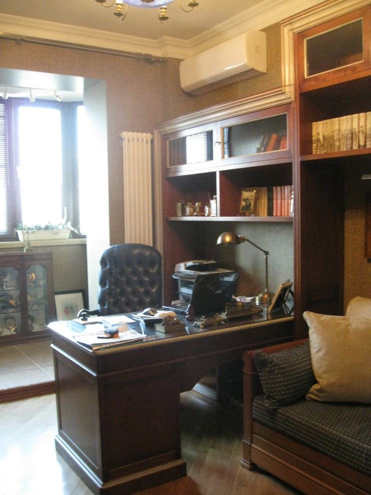 Exempel på ett stort klassiskt hemmabibliotek, med vita väggar, ett fristående skrivbord, mellanmörkt trägolv och beiget golv