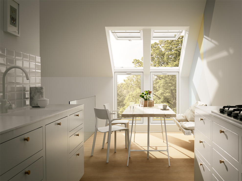 Inspiration for a small scandinavian galley separate kitchen in Dusseldorf with an integrated sink, flat-panel cabinets, white cabinets, white splashback, ceramic splashback, light hardwood floors, no island, brown floor and white benchtop.