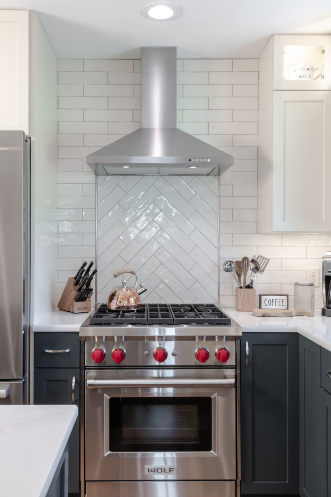 Enclosed kitchen - transitional l-shaped light wood floor enclosed kitchen idea in St Louis with an undermount sink, shaker cabinets, green cabinets, quartz countertops, white backsplash, subway tile backsplash, stainless steel appliances, an island and white countertops