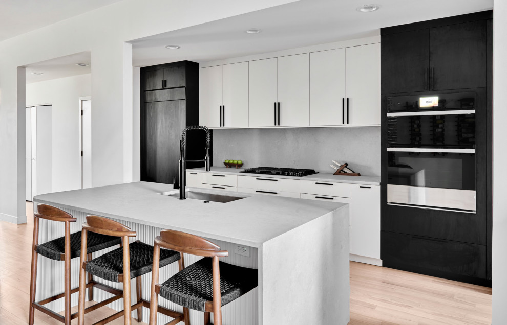 Large contemporary u-shaped kitchen/diner in Chicago with a submerged sink, flat-panel cabinets, white cabinets, quartz worktops, white splashback, porcelain splashback, black appliances, an island and white worktops.