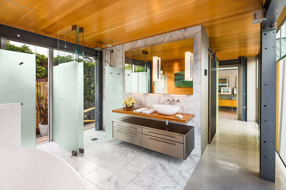 This is an example of a small contemporary master bathroom in Los Angeles with a vessel sink, wood benchtops, a freestanding tub, a curbless shower, white tile, concrete floors and flat-panel cabinets.