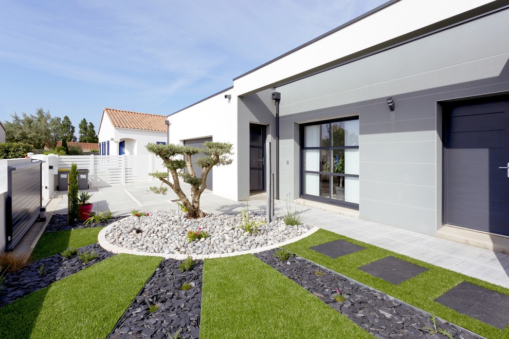 Photo of a mid-sized contemporary front yard full sun driveway for spring in Nantes with a garden path and gravel.