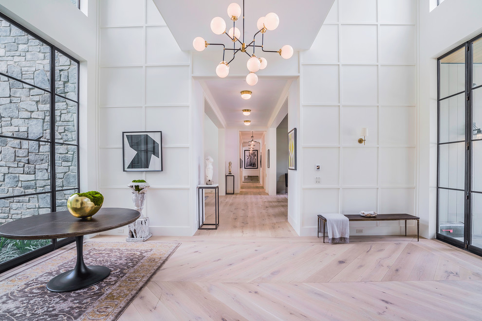 Inspiration for an expansive contemporary foyer in Los Angeles with white walls, light hardwood floors, a metal front door and a double front door.