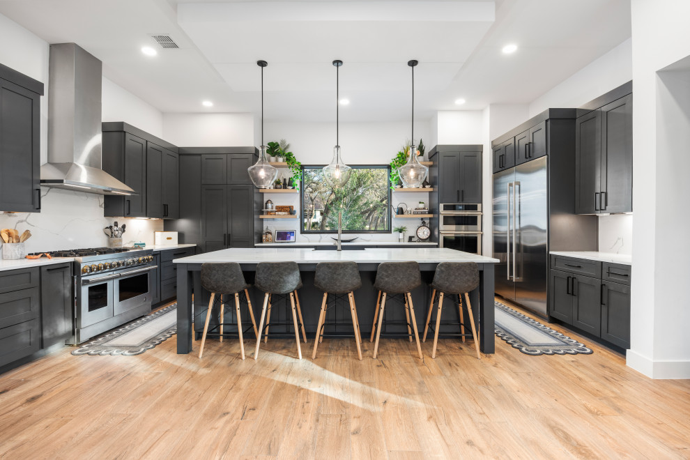 Kitchen - transitional u-shaped light wood floor and beige floor kitchen idea in Austin with a farmhouse sink, shaker cabinets, gray cabinets, stainless steel appliances, an island and white countertops