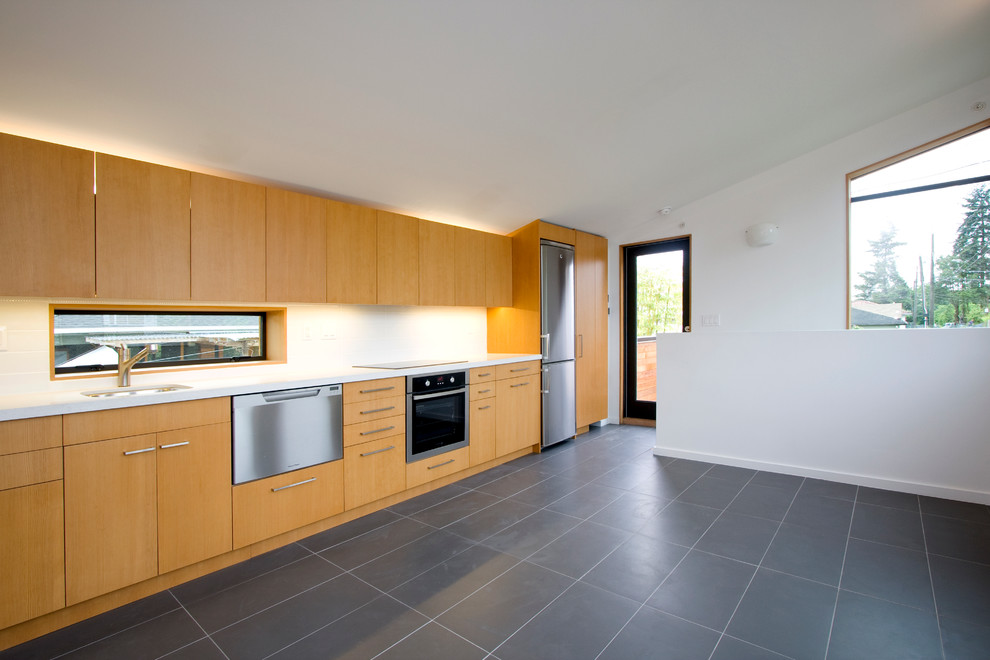Modern single-wall open plan kitchen in Vancouver with an undermount sink, flat-panel cabinets, light wood cabinets, quartz benchtops, white splashback, ceramic splashback, stainless steel appliances, ceramic floors and no island.