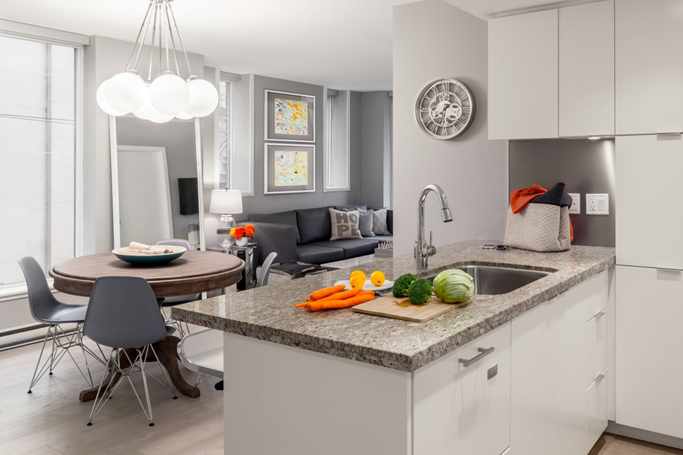 Design ideas for a mid-sized modern u-shaped eat-in kitchen in Vancouver with a single-bowl sink, flat-panel cabinets, white cabinets, granite benchtops, grey splashback, panelled appliances, porcelain floors and no island.