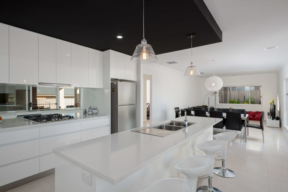 Inspiration for a contemporary eat-in kitchen in Sydney with a drop-in sink, solid surface benchtops, mirror splashback, stainless steel appliances and porcelain floors.