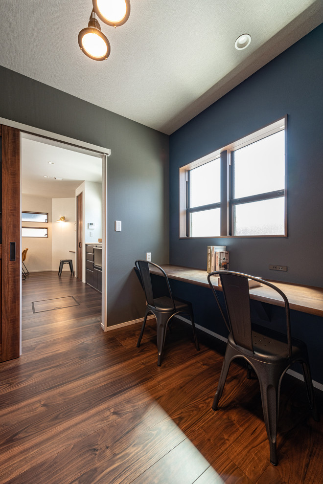 Foto de despacho gris minimalista de tamaño medio sin chimenea con paredes grises, suelo de contrachapado, escritorio empotrado, suelo marrón, papel pintado y papel pintado