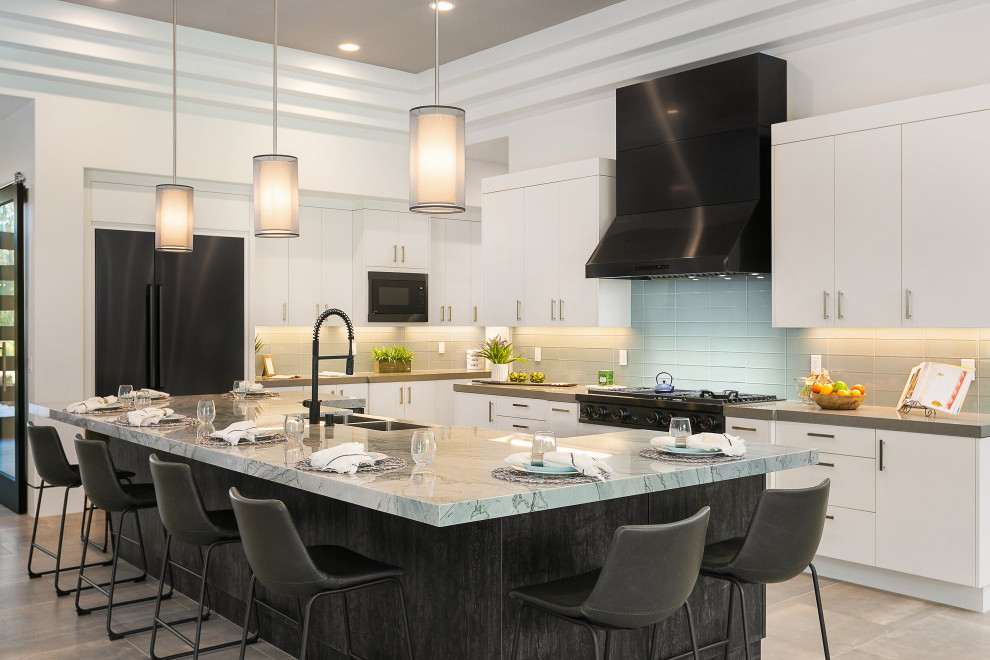 Contemporary kitchen in San Diego with a farmhouse sink, flat-panel cabinets, white cabinets, quartzite benchtops, blue splashback, glass tile splashback, black appliances, porcelain floors, with island, grey floor and grey benchtop.