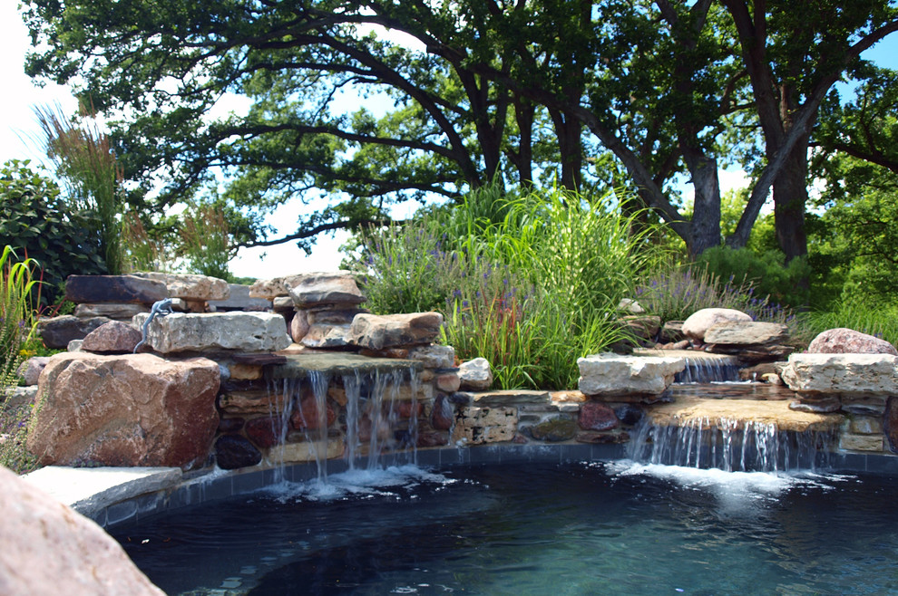 Large arts and crafts backyard custom-shaped natural pool in Chicago with a water feature and natural stone pavers.