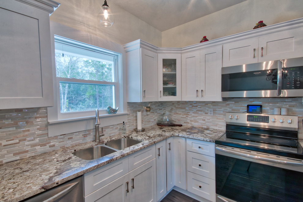 Mid-sized l-shaped eat-in kitchen photo with an undermount sink, shaker cabinets, yellow cabinets, granite countertops, glass tile backsplash, stainless steel appliances, an island and white countertops