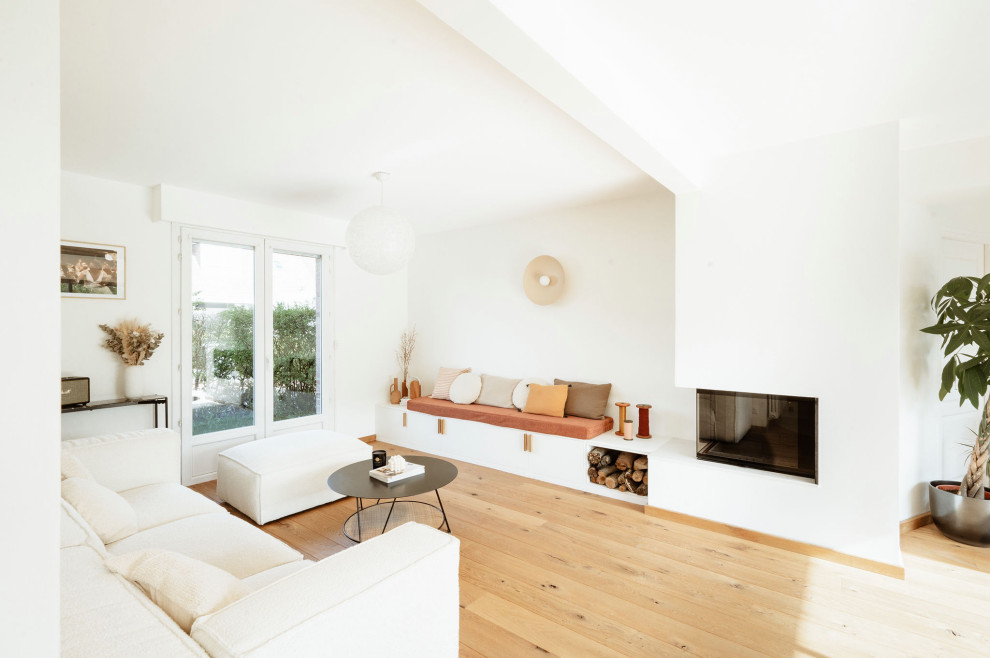 Cette image montre un salon blanc et bois minimaliste de taille moyenne et ouvert avec un mur blanc, parquet clair, une cheminée d'angle et aucun téléviseur.