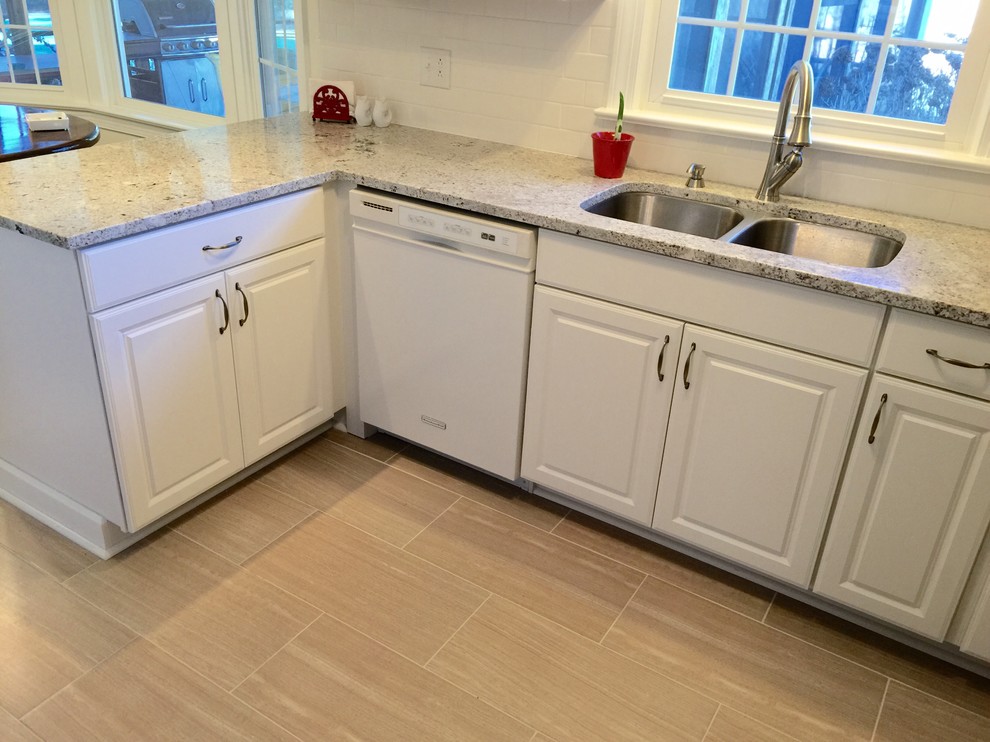 Mid-sized transitional u-shaped porcelain tile enclosed kitchen photo with an undermount sink, raised-panel cabinets, white cabinets, granite countertops, white backsplash, subway tile backsplash, stainless steel appliances and a peninsula