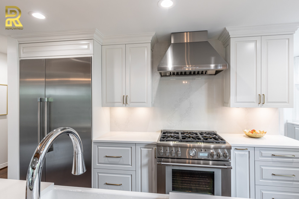 Photo of a large transitional open plan kitchen in Dallas with a farmhouse sink, shaker cabinets, white cabinets, quartz benchtops, white splashback, engineered quartz splashback, stainless steel appliances, medium hardwood floors, with island and white benchtop.