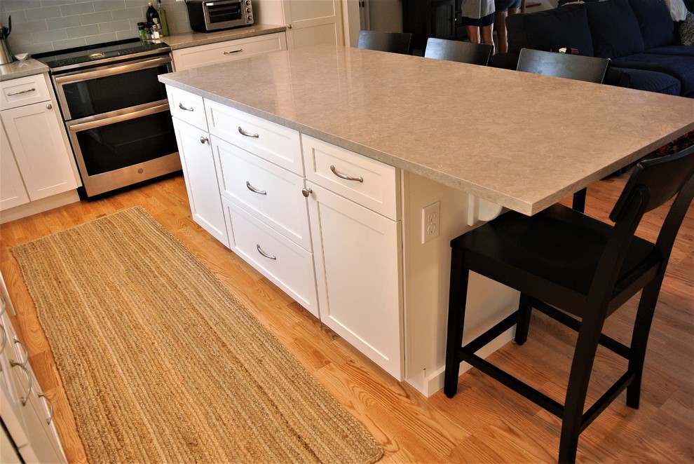 Kitchen - transitional light wood floor kitchen idea in Boston with an undermount sink, shaker cabinets, white cabinets, quartz countertops, gray backsplash, subway tile backsplash, stainless steel appliances, an island and gray countertops
