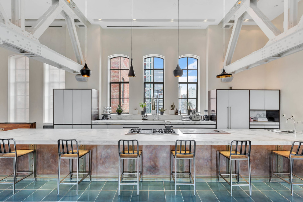 Design ideas for an expansive industrial galley kitchen in New York with flat-panel cabinets, white cabinets, marble benchtops, panelled appliances, with island, green floor and grey benchtop.