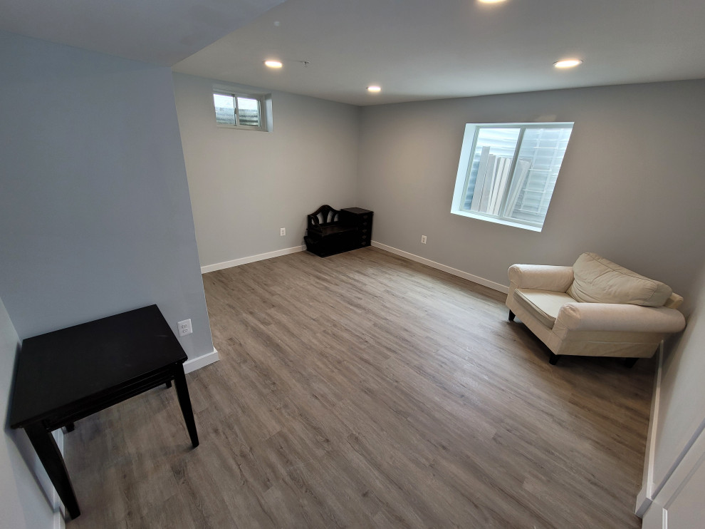 Photo of a large contemporary fully buried basement in DC Metro with a game room, grey walls, vinyl flooring, a corner fireplace and brown floors.