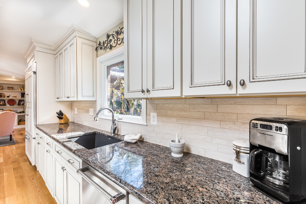 Inspiration for an expansive transitional galley open plan kitchen in DC Metro with a single-bowl sink, beaded inset cabinets, white cabinets, granite benchtops, white splashback, porcelain splashback, stainless steel appliances, light hardwood floors, with island and brown floor.