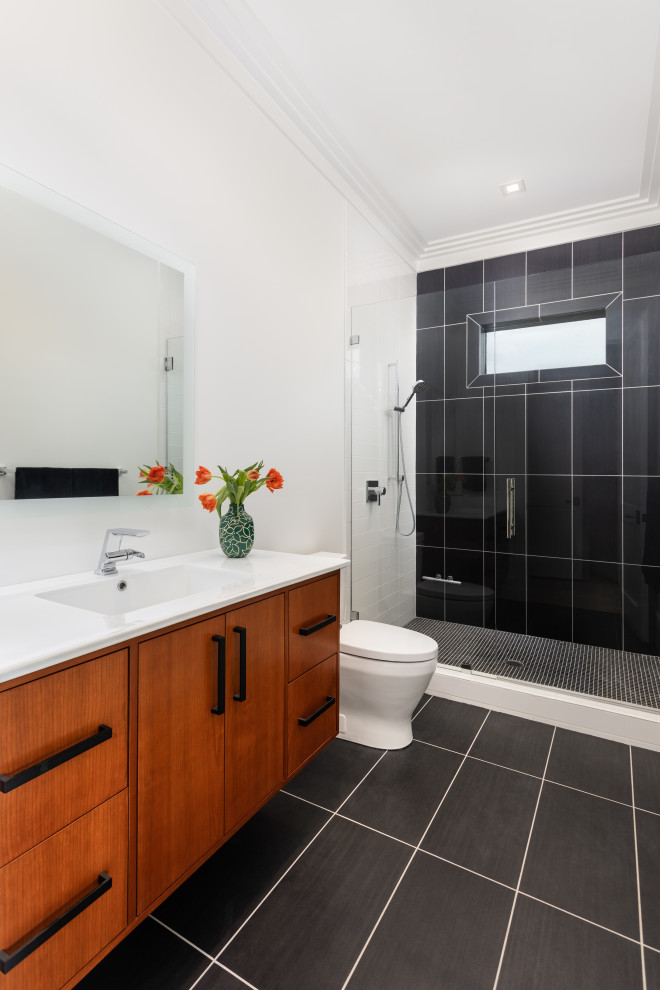 Bathroom - large contemporary black and white tile and ceramic tile ceramic tile, black floor and single-sink bathroom idea in Other with flat-panel cabinets, dark wood cabinets, a one-piece toilet, white walls, an integrated sink, solid surface countertops, white countertops and a floating vanity