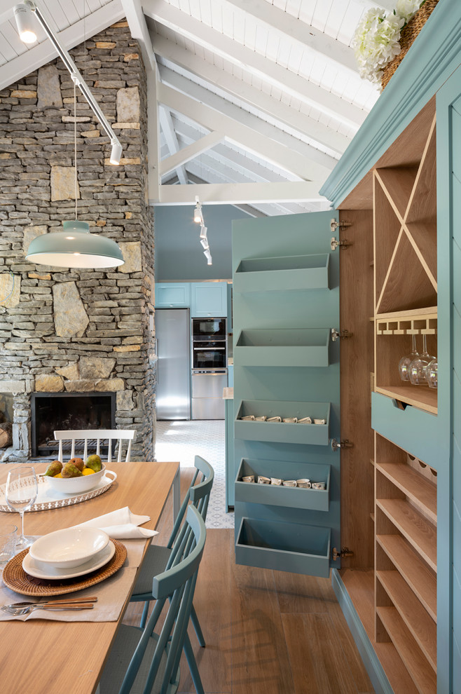 Modelo de comedor de cocina tradicional renovado extra grande con paredes azules, suelo laminado, todas las chimeneas, marco de chimenea de piedra y suelo marrón