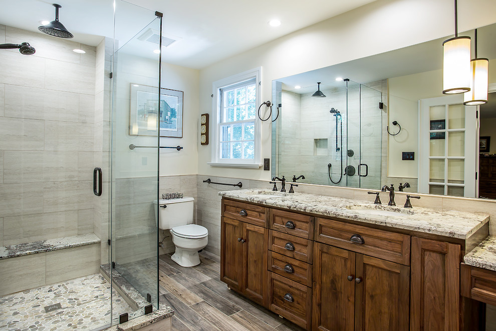 Example of a large mountain style master beige tile and porcelain tile gray floor and porcelain tile corner shower design in Richmond with dark wood cabinets, a two-piece toilet, gray walls, an undermount sink, granite countertops, a hinged shower door and shaker cabinets