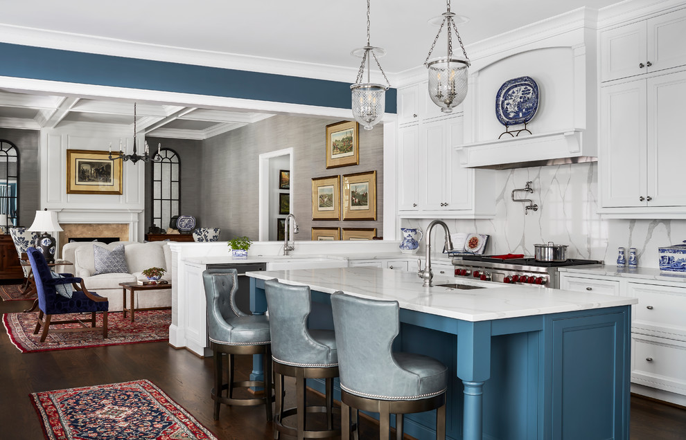 This is an example of a mid-sized traditional u-shaped open plan kitchen in Atlanta with white cabinets, white splashback, stone slab splashback, stainless steel appliances, dark hardwood floors, with island, brown floor, white benchtop, a farmhouse sink, beaded inset cabinets and quartzite benchtops.