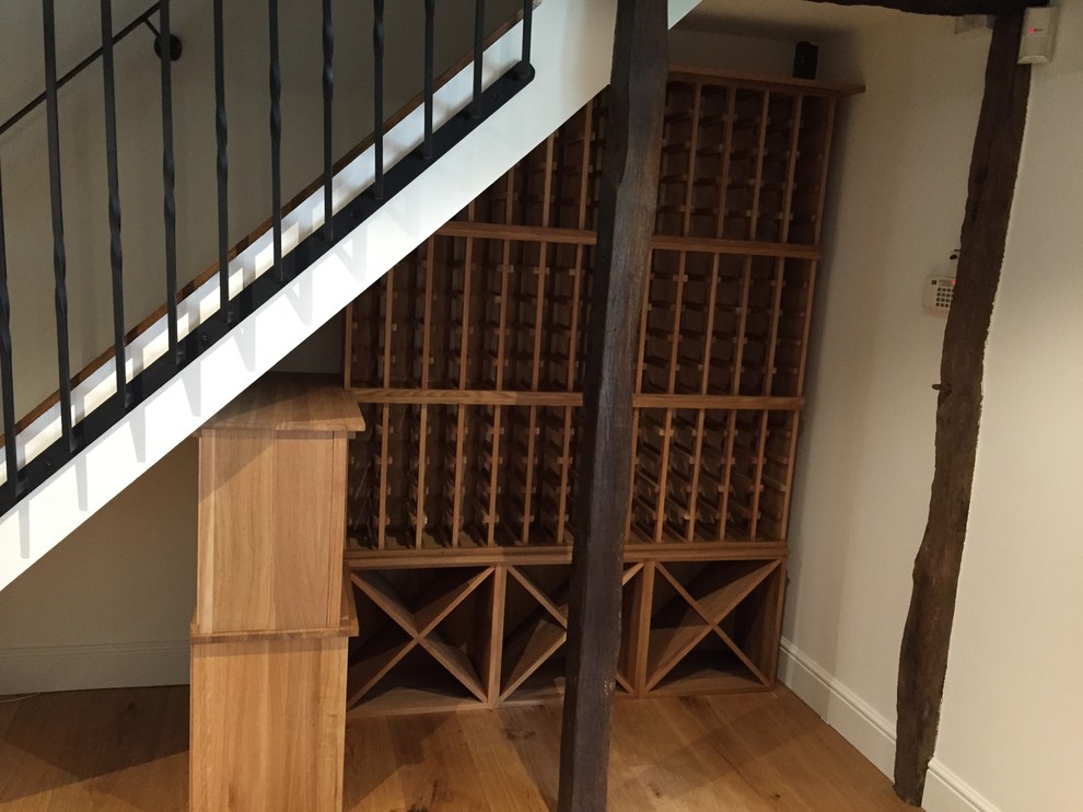 Small contemporary wine cellar in Hertfordshire with storage racks, light hardwood floors and brown floor.
