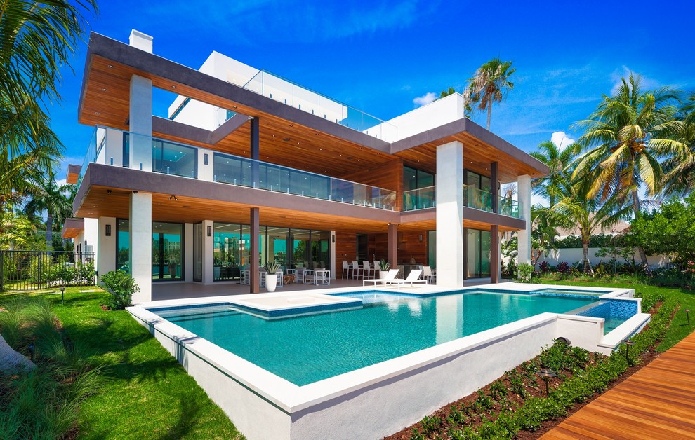 This is an example of a contemporary backyard custom-shaped lap pool in Miami with a hot tub.