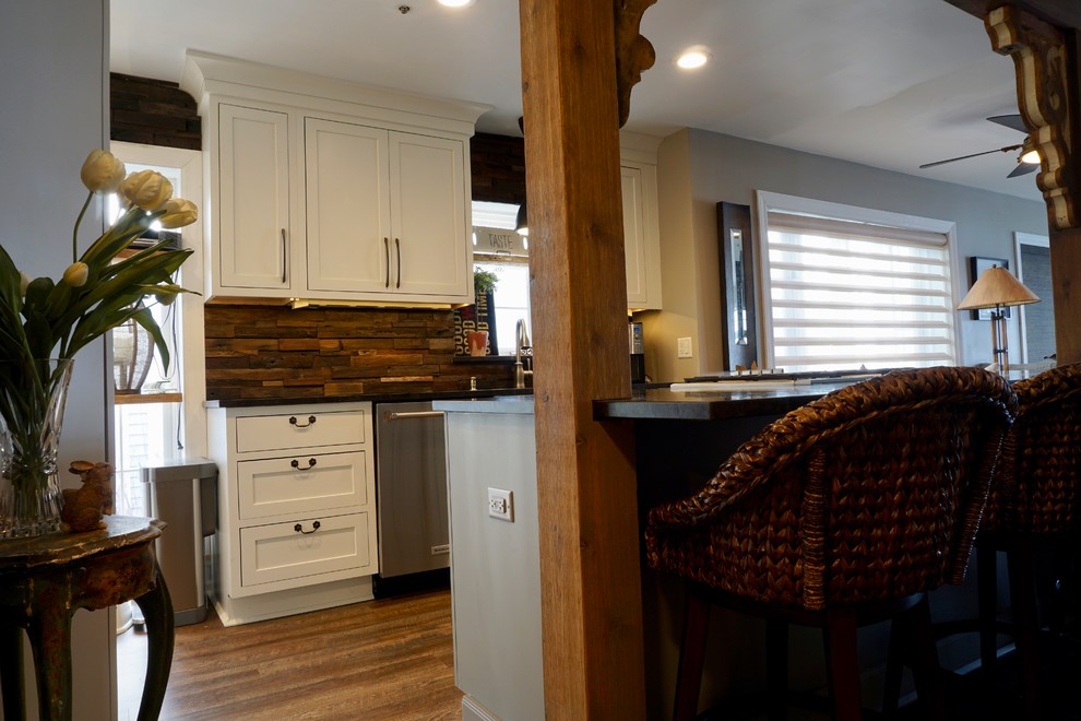 This is an example of a small country galley eat-in kitchen in Chicago with a single-bowl sink, shaker cabinets, white cabinets, granite benchtops, brown splashback, timber splashback, stainless steel appliances, dark hardwood floors, with island and brown floor.