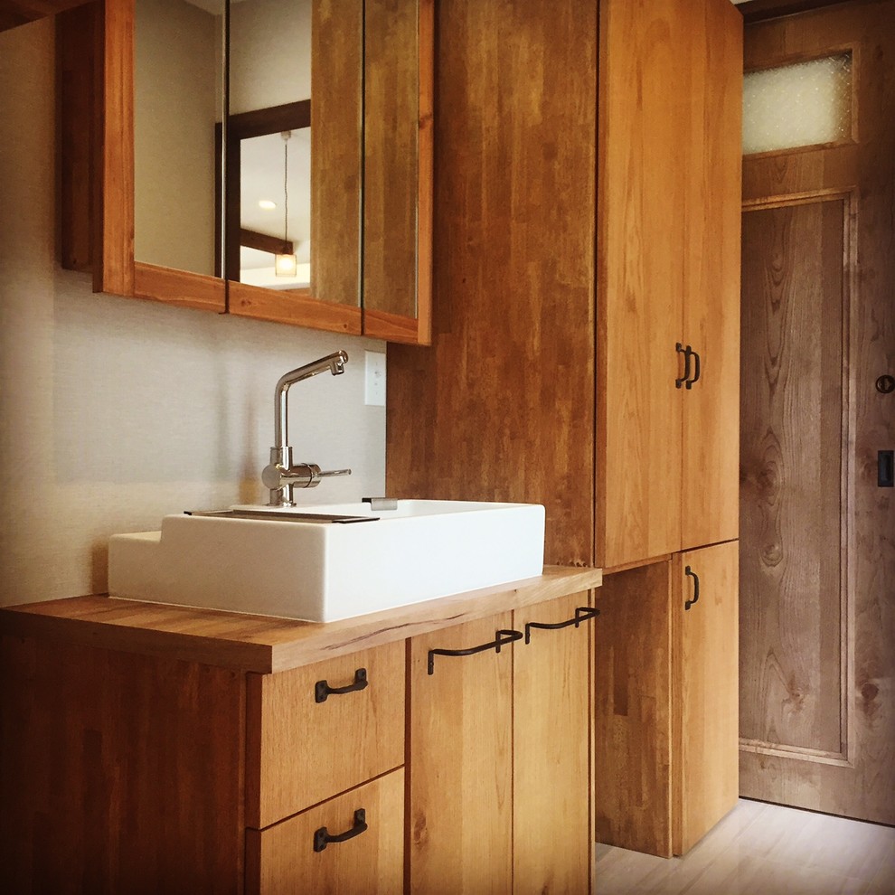 Industrial powder room in Other with flat-panel cabinets, medium wood cabinets, white walls, a vessel sink, wood benchtops, beige floor and brown benchtops.