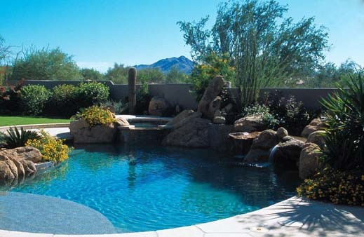 Mid-sized mountain style backyard stone and custom-shaped natural hot tub photo in Phoenix
