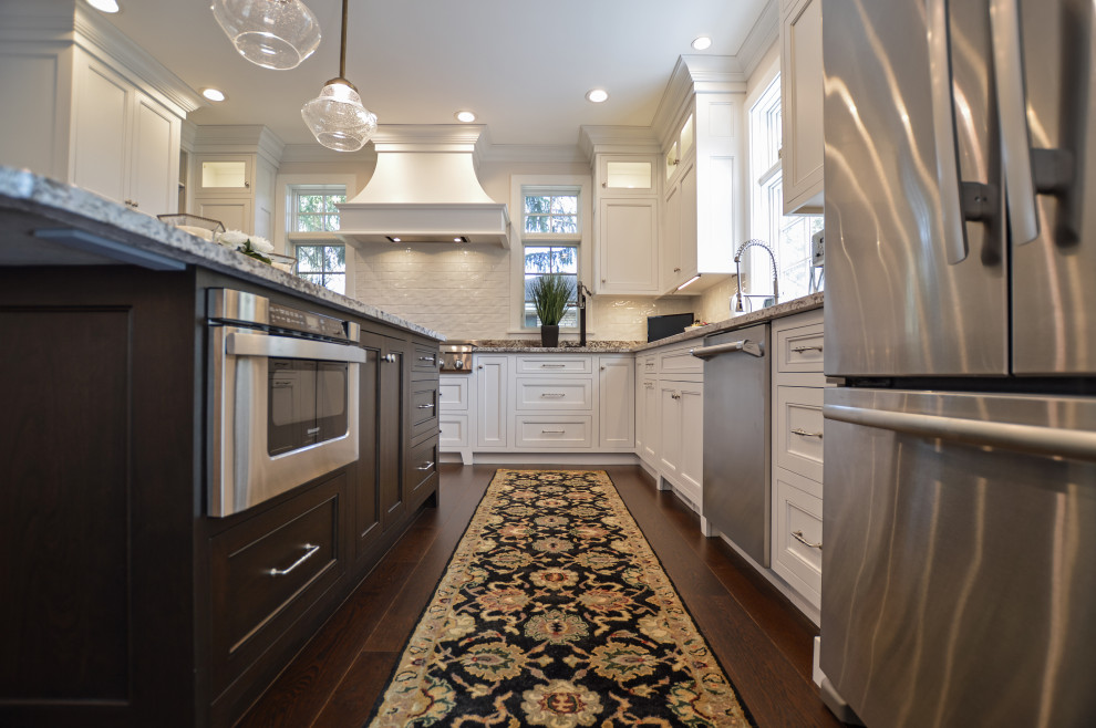 Inspiration for a transitional dark wood floor and brown floor eat-in kitchen remodel with an undermount sink, shaker cabinets, white cabinets, granite countertops, white backsplash, ceramic backsplash, stainless steel appliances, an island and beige countertops
