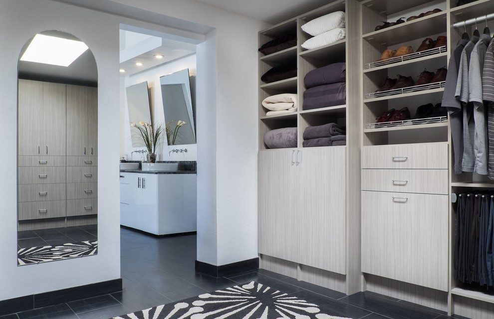This is an example of a large modern gender-neutral dressing room in Other with flat-panel cabinets, light wood cabinets, porcelain floors and black floor.