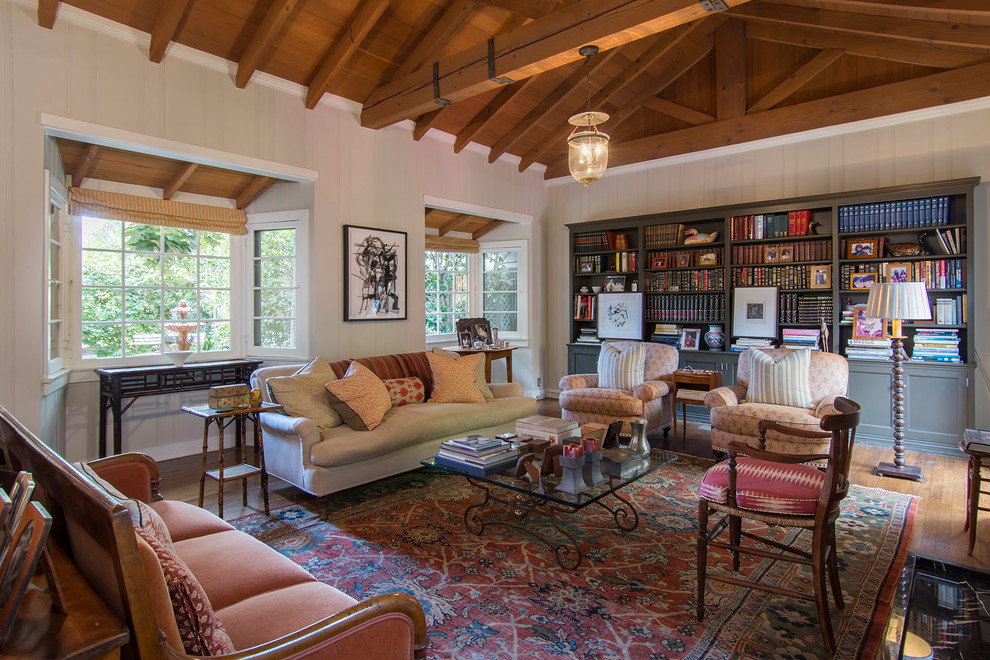 Photo of a traditional living room in Los Angeles with a library, white walls, medium hardwood floors and brown floor.