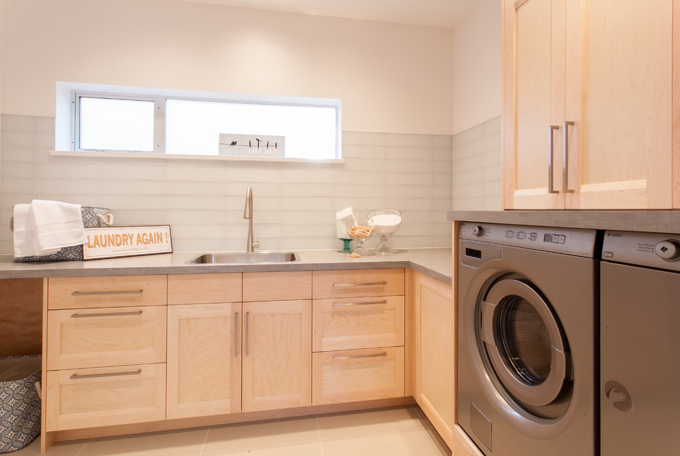 Inspiration for a mid-sized contemporary dedicated laundry room in Vancouver with a single-bowl sink, shaker cabinets, light wood cabinets, laminate benchtops, white walls, porcelain floors and a side-by-side washer and dryer.