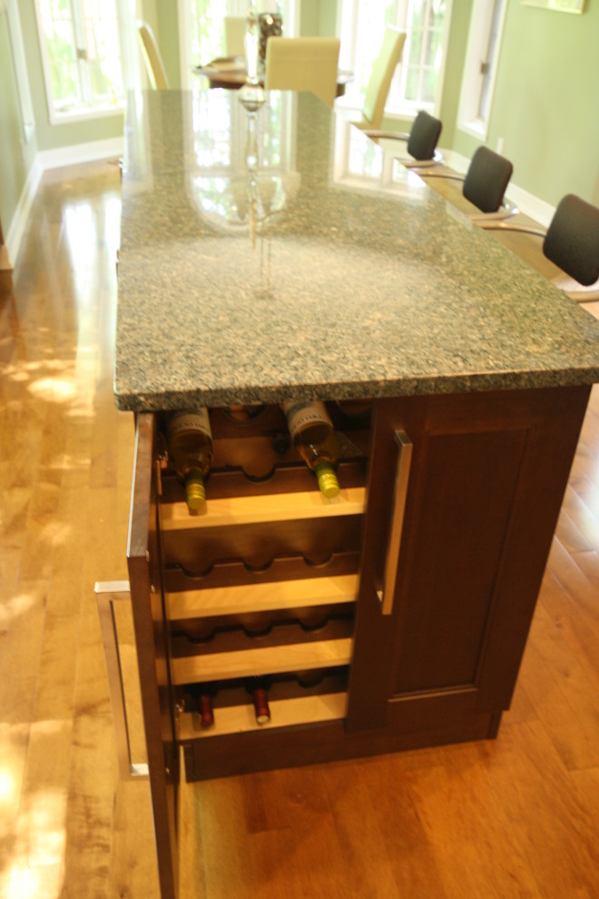 Mid-sized transitional u-shaped light wood floor and beige floor enclosed kitchen photo in Ottawa with a double-bowl sink, recessed-panel cabinets, dark wood cabinets, granite countertops, metallic backsplash, glass tile backsplash, stainless steel appliances, an island and brown countertops