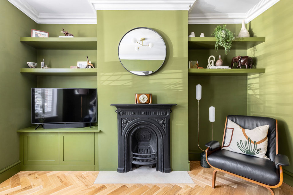 Inredning av ett klassiskt mellanstort separat vardagsrum, med ett finrum, gröna väggar, mellanmörkt trägolv, en standard öppen spis, en spiselkrans i metall, TV i ett hörn och beiget golv