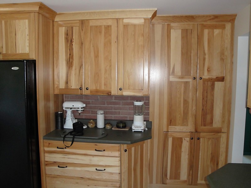 Eat-in kitchen - mid-sized rustic u-shaped eat-in kitchen idea with flat-panel cabinets, light wood cabinets, solid surface countertops, a peninsula, black appliances and gray countertops