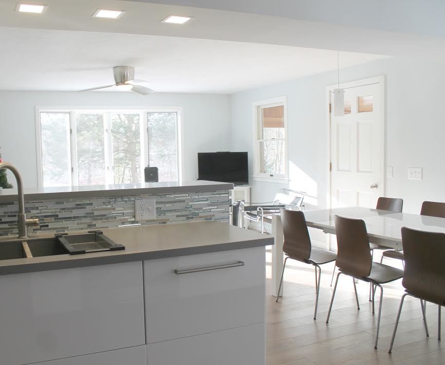 Example of a mid-sized transitional medium tone wood floor and brown floor eat-in kitchen design with a double-bowl sink, flat-panel cabinets, white cabinets, solid surface countertops, multicolored backsplash, matchstick tile backsplash, stainless steel appliances and no island