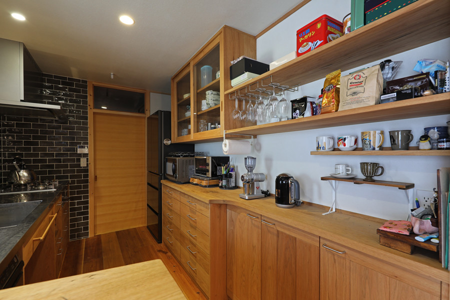 Photo of a mid-sized asian galley eat-in kitchen in Other with an integrated sink, open cabinets, wood benchtops, porcelain splashback, stainless steel appliances, medium hardwood floors and no island.