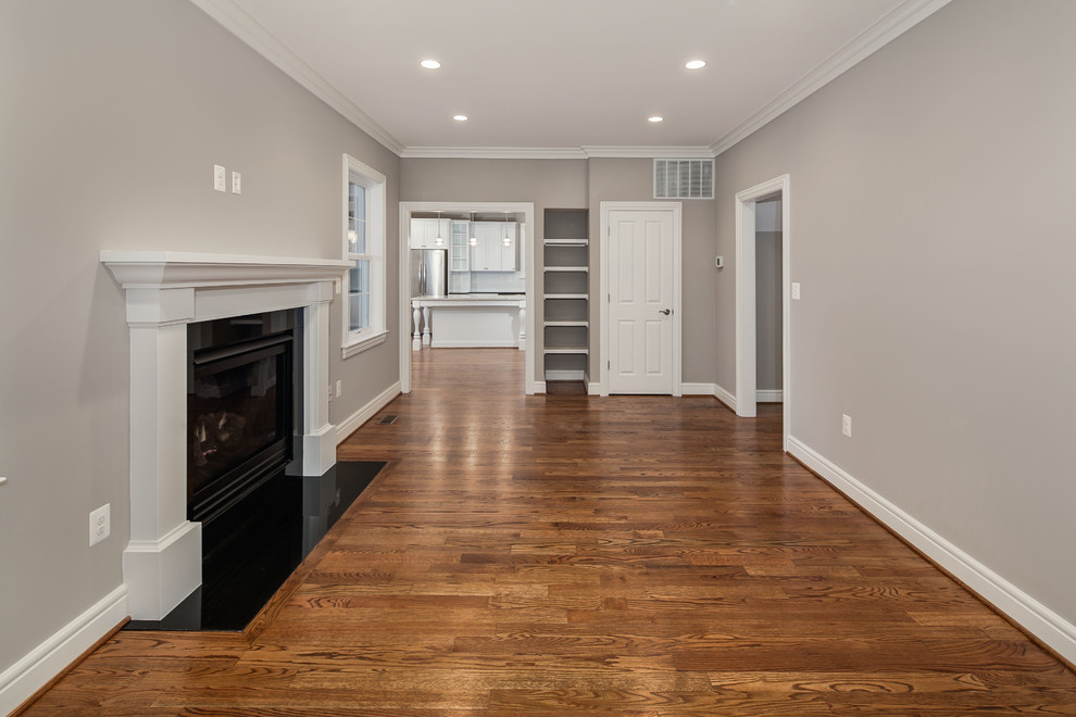 This is an example of a large transitional formal enclosed living room in DC Metro with grey walls, medium hardwood floors, a standard fireplace, a plaster fireplace surround and no tv.