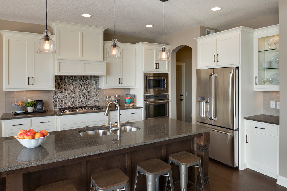 Example of a transitional dark wood floor kitchen design in Minneapolis with a double-bowl sink, white cabinets, quartzite countertops, multicolored backsplash, mosaic tile backsplash, stainless steel appliances and an island