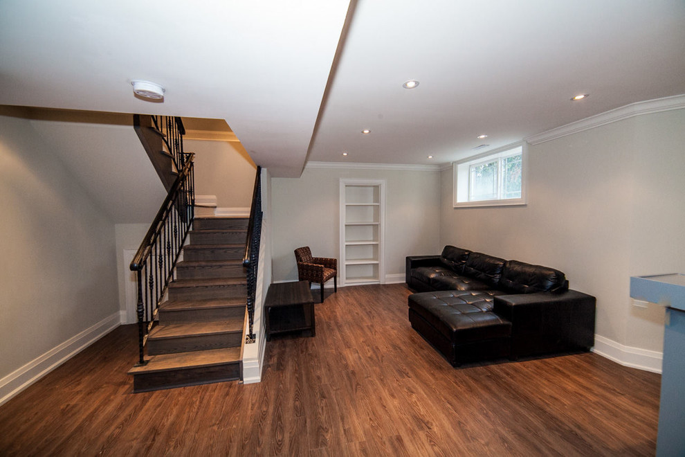 This is an example of a mid-sized modern look-out basement in Toronto with beige walls, dark hardwood floors, no fireplace and brown floor.