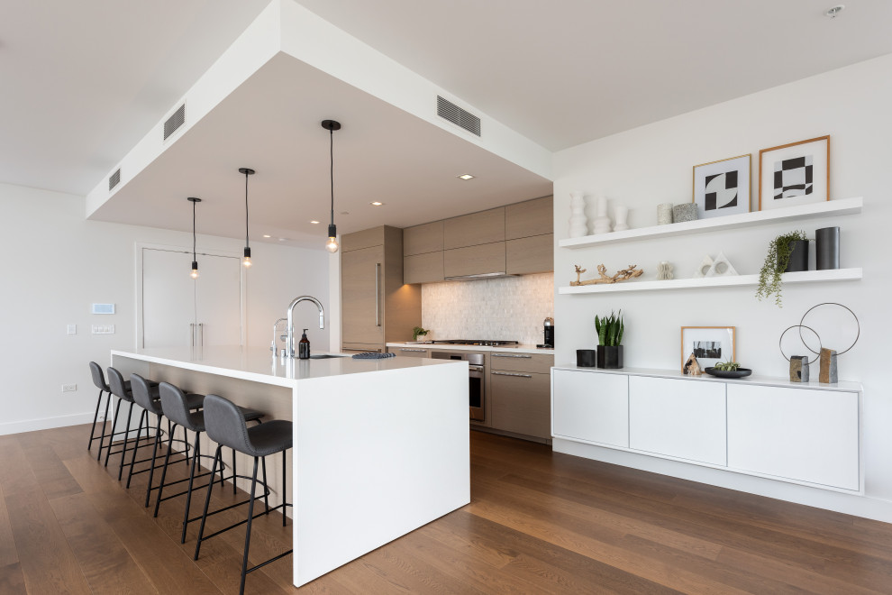 Inspiration for a contemporary galley kitchen in San Diego with flat-panel cabinets, light wood cabinets, quartz benchtops, white splashback, marble splashback, panelled appliances, medium hardwood floors, with island and brown floor.