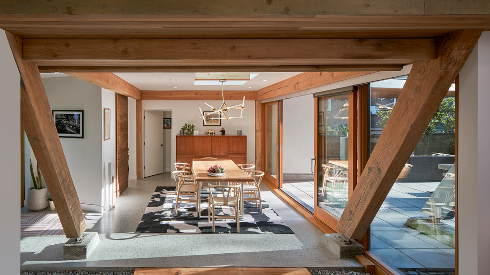 Large midcentury open plan dining in Vancouver with white walls, concrete floors and grey floor.
