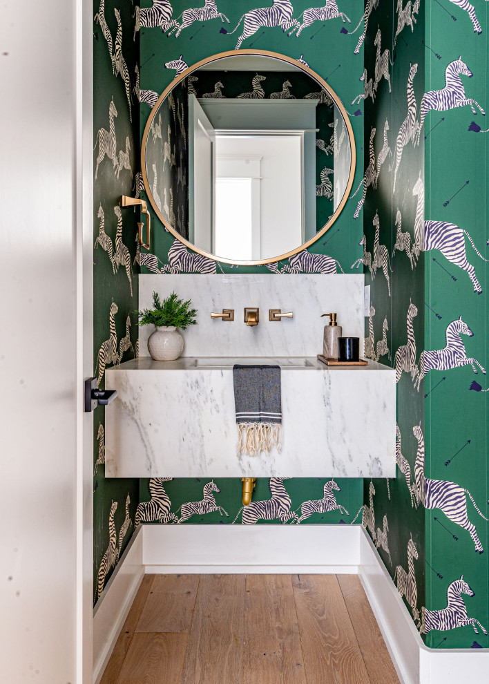 This is an example of a small transitional powder room in Los Angeles with green walls, light hardwood floors, an integrated sink, marble benchtops, white benchtops, a floating vanity and wallpaper.