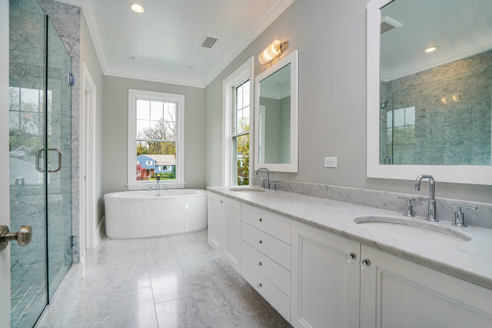 This is an example of a large transitional master bathroom in New York with recessed-panel cabinets, white cabinets, a freestanding tub, an alcove shower, a two-piece toilet, gray tile, white tile, stone slab, grey walls, marble floors, an undermount sink, soapstone benchtops, multi-coloured floor and a hinged shower door.